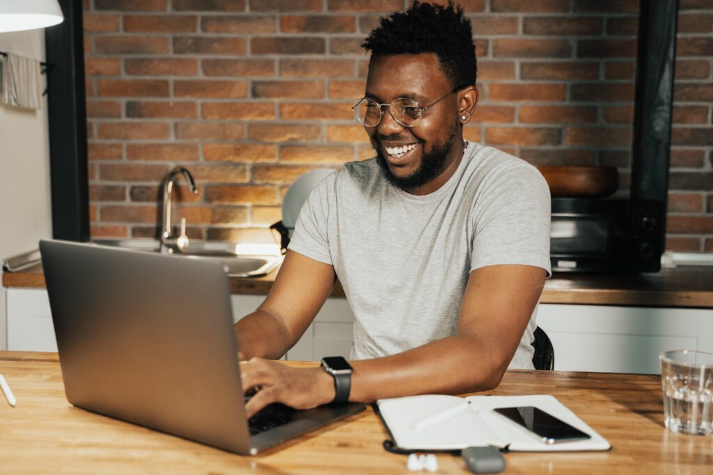 A man in front of his laptop happily working on something. 